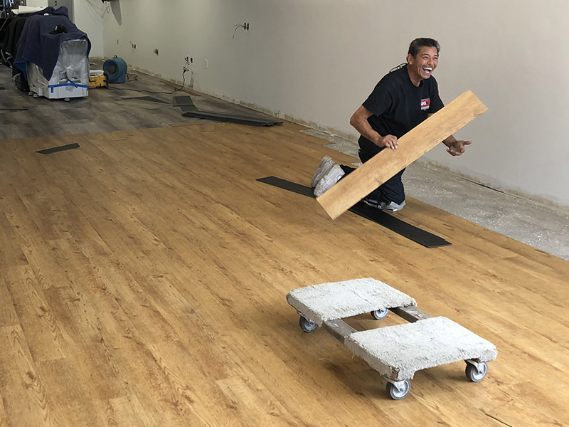 Photo of contractor smiling and laying down flooring